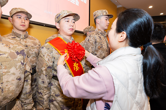 辅导员为入伍新兵佩戴绥带和大红花。厦门城市职业学院供图